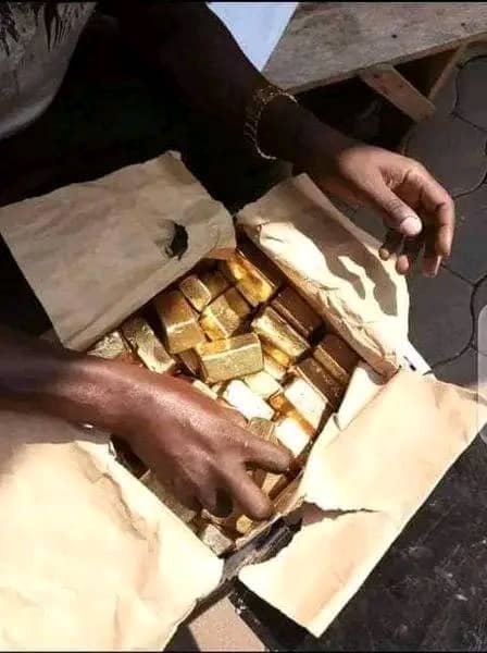 Open paper parcel packed with small cast gold bars held by a trader